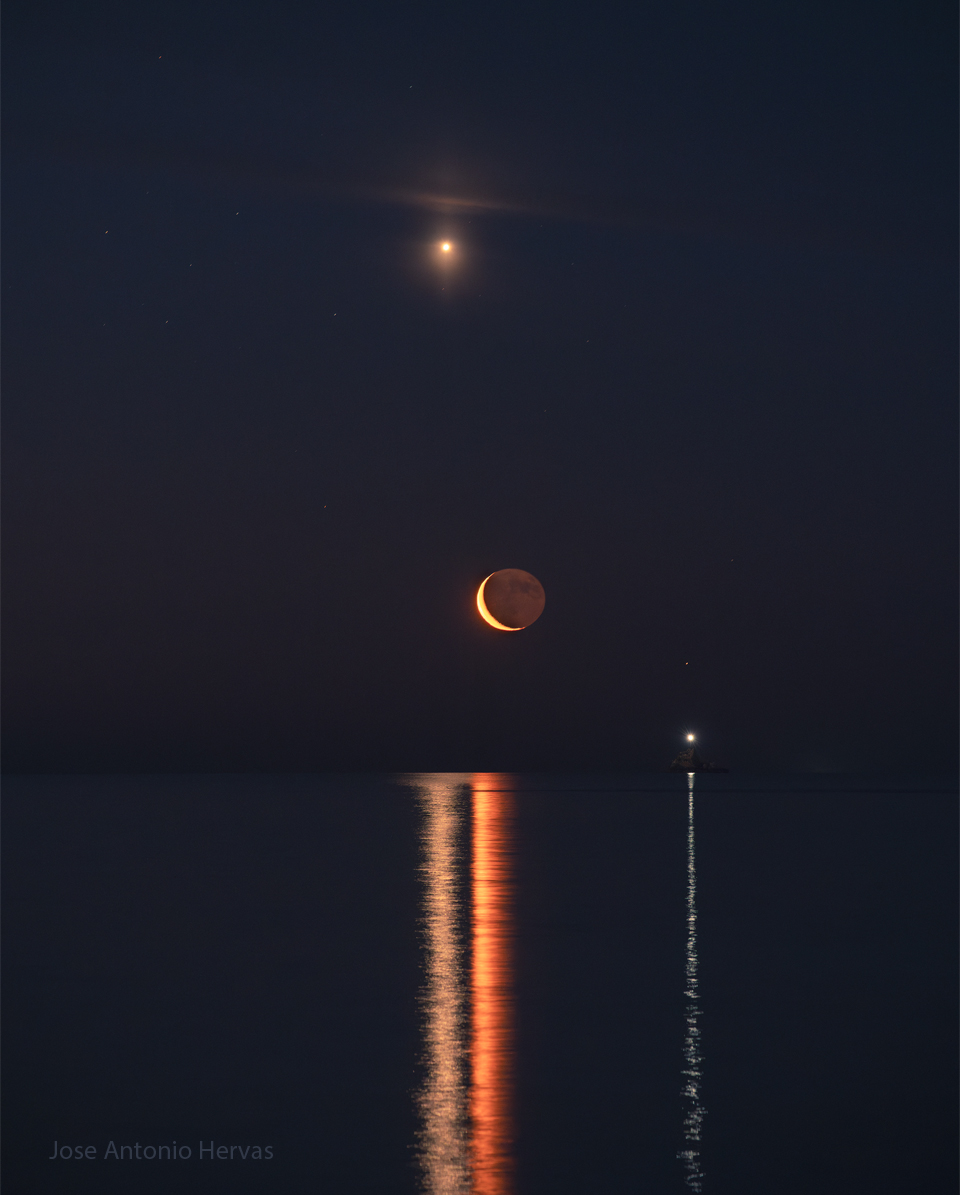 The featured image shows a night sky over some choppy
water. The planet Venus shines high in the night sky, while a faint
Saturn in on the far right. The crescent Moon is visible near the
image centre. A bright boat beacon is also visible on the right.
All of these objects are reflected as lines in the foreground
water.
Please see the explanation for more detailed information.