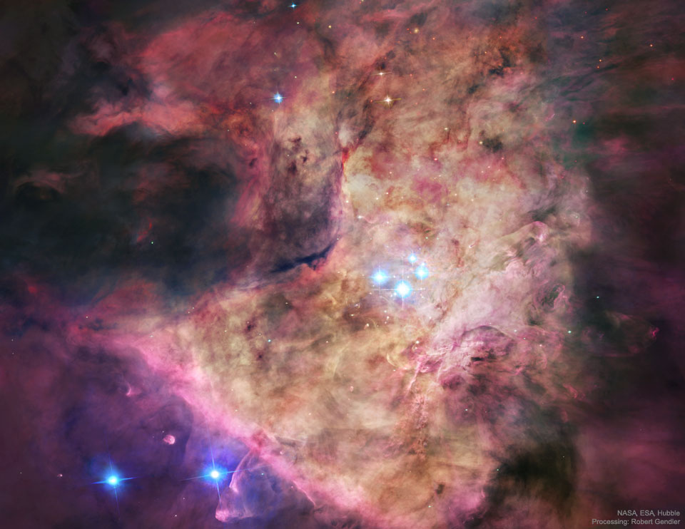 A bright nebula occupies the centre of the frame. 
The nebula is complex but roughly tan in the centre and
red around the edges. In the centre are four bright blue stars.
Please see the explanation for more detailed information.