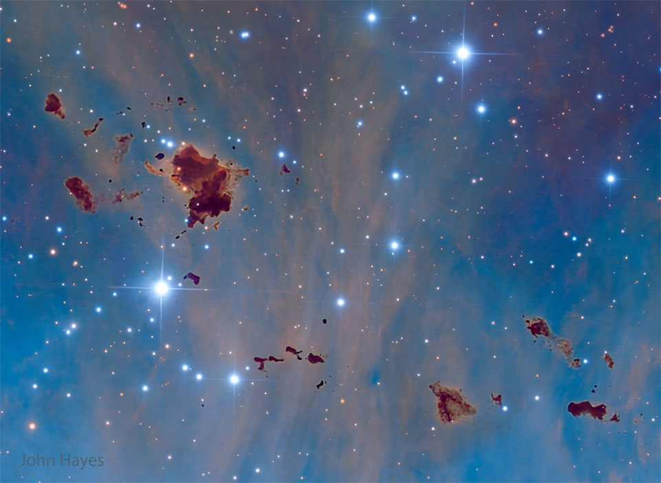 A starfield with a blue background shows several
unusual brown globs. They are generally irregularly 
shaped.
Please see the explanation for more detailed information.