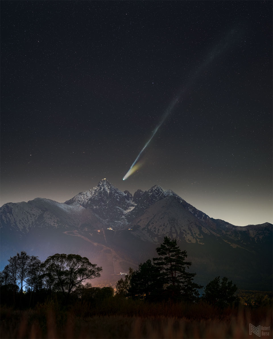 An image of the night sky over distant mountains
features a comet with long tails. One of the tails
goes nearly to the edge of the picture on the upper right.
Please see the explanation for more detailed information.