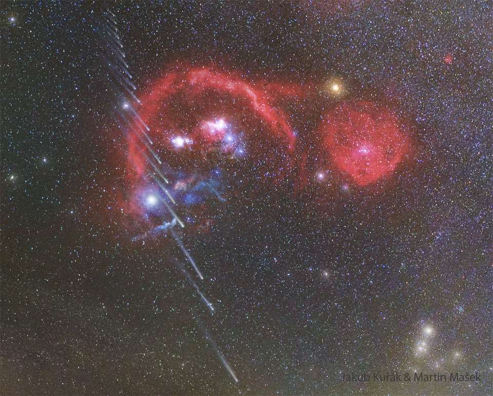 A starfield shows many red nebulae near the centre. 
Running vertically up the left side are about 20 images of a
comet, with the head towards the image bottom.  Successively
higher images of the comet show successively shorter
tails. 
Please see the explanation for more detailed information.