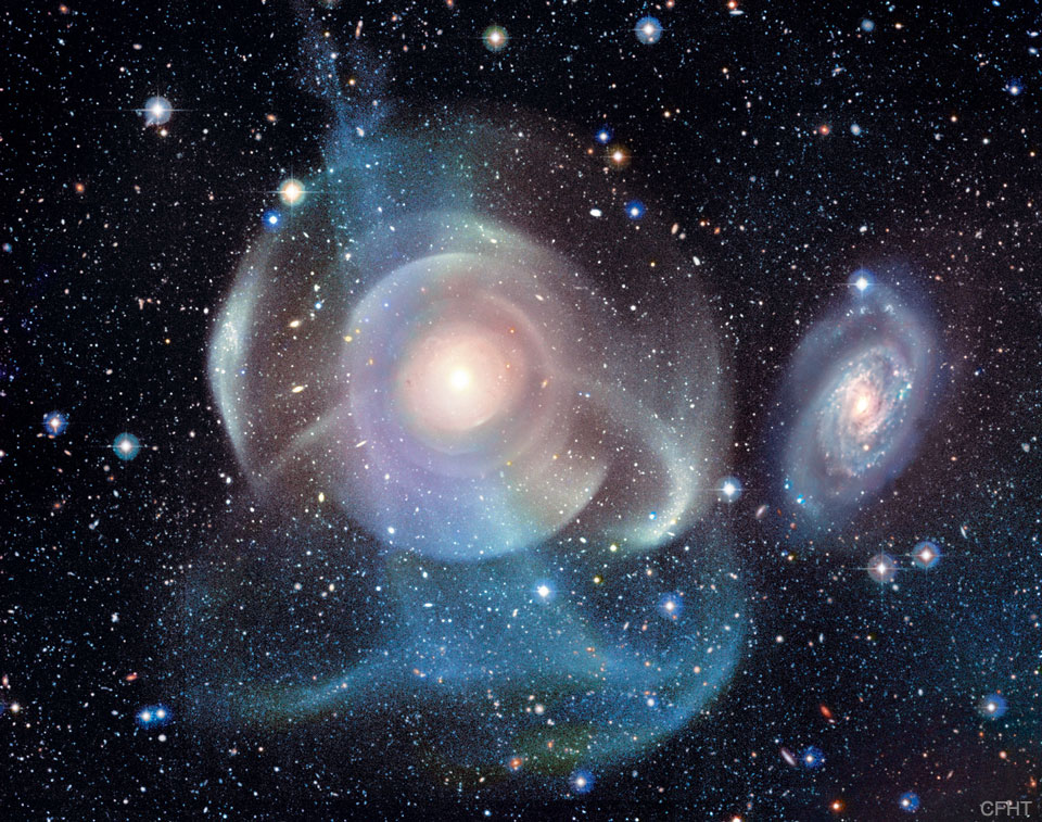 A starfield surrounds a complex background galaxy.
The galaxy centre is surrounded by numerous shells, some
circular and concentric, but others colourful and 
filamentary. 
Please see the explanation for more detailed information.