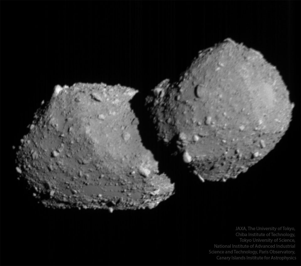 A large rocky object floats in dark space. The
object is gray and has many small protrusions. 
Please see the explanation for more detailed information.