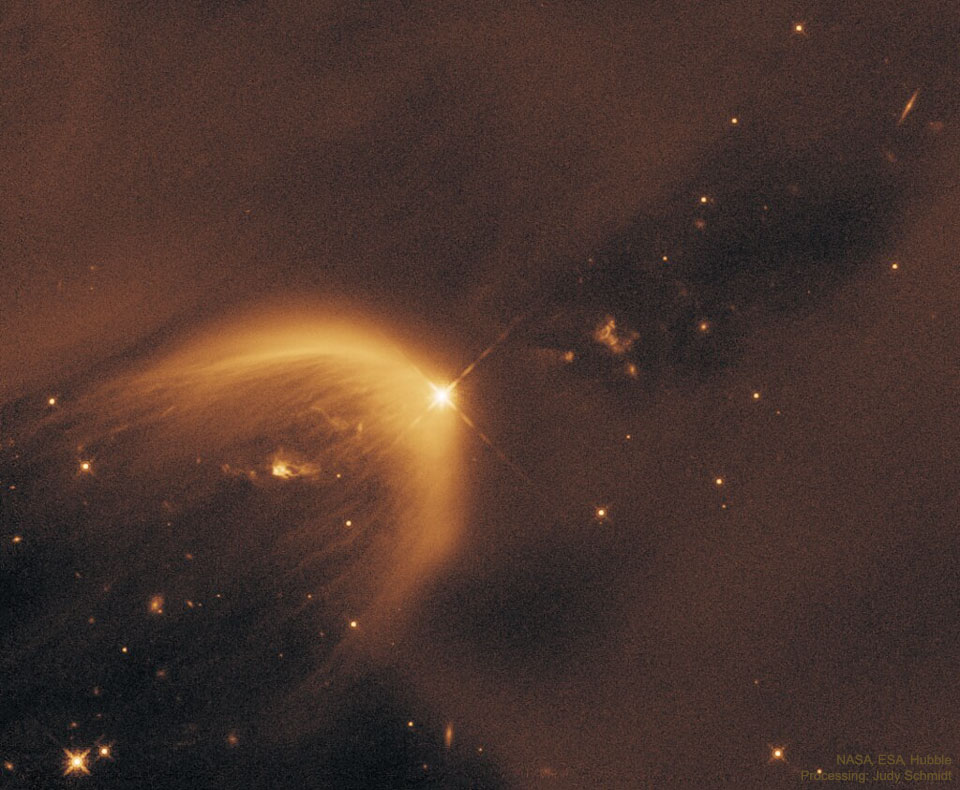 A starfield is dominated by light brown dust. In the 
middle is a parabolic gas cloud opening toward the lower right.
A bright star is near the centre at the apex of the parabolic
gas cloud. 
Please see the explanation for more detailed information.