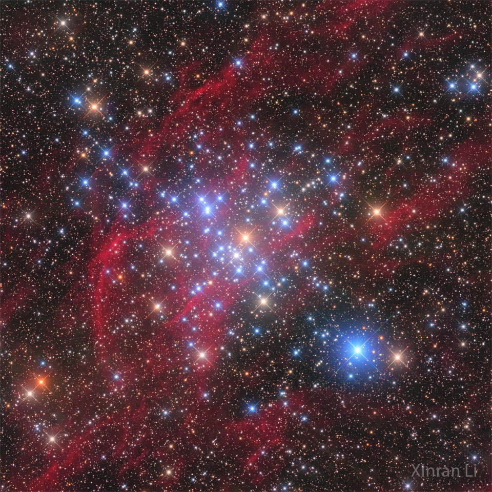 A starscape is shown with red filaments running 
diagonally from the lower left to the upper right.
Many bright blue stars are visible across the centre
of the frame. 
Please see the explanation for more detailed information.